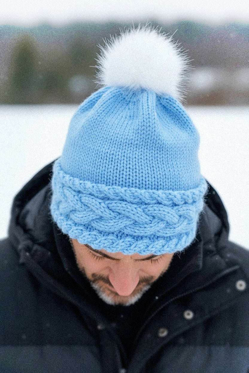 Adult wearing cable knit bobble beanie made using a knitting pattern