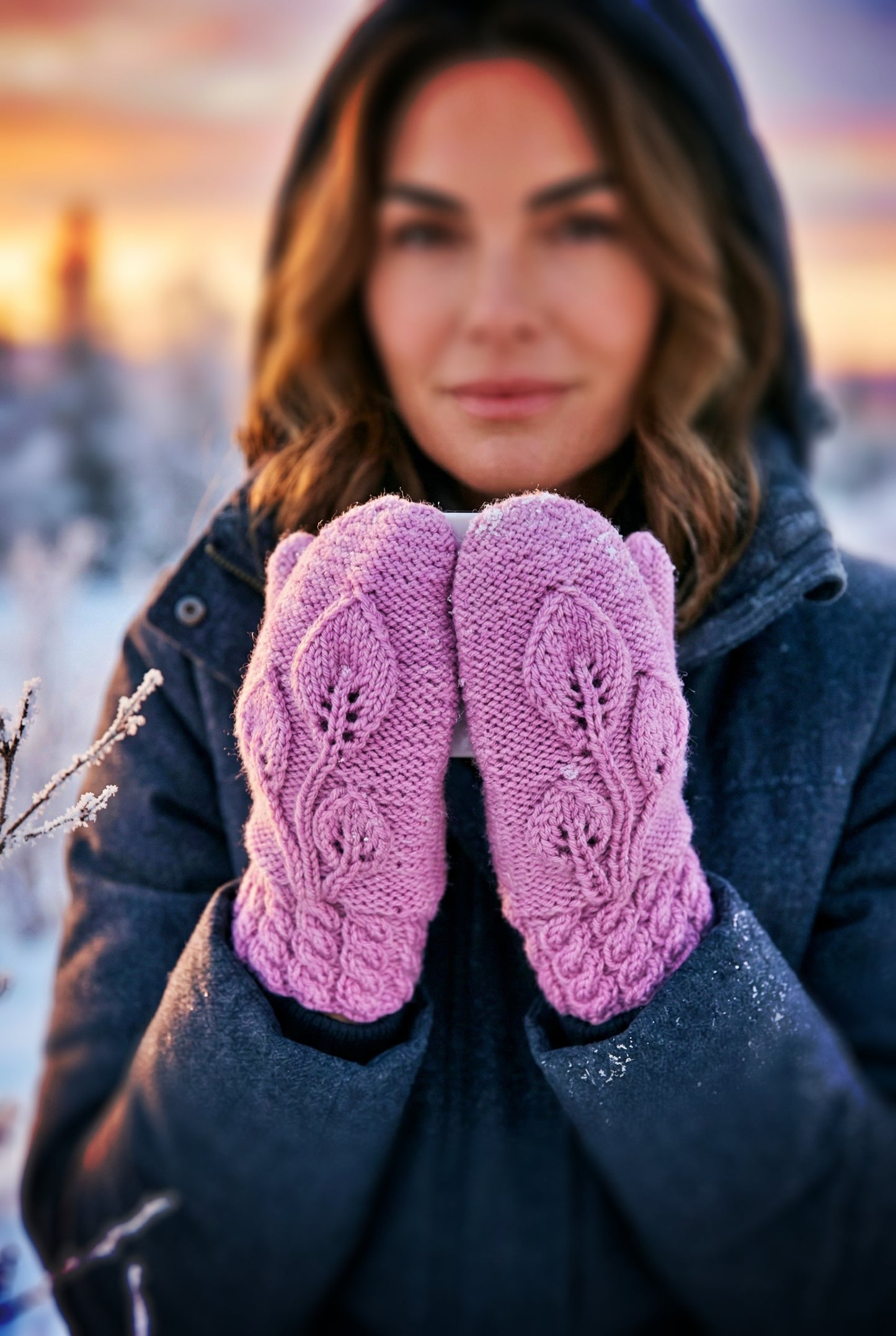 Woman wearing pink mittens with a blurred winter background