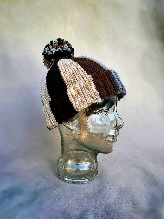 Knitted hat with a pom-pom on a mannequin head against a neutral background
